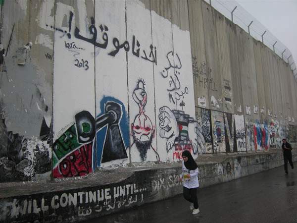 Due giovani corridori in corsa lungo il muro israeliano che separa Betlemme da Gerusalemme.